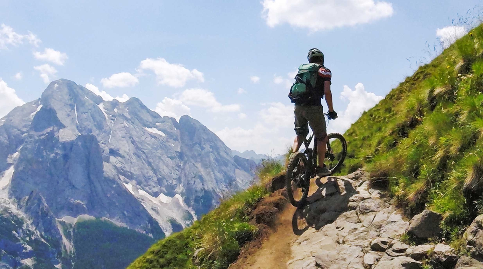 A person on a mountain bike with a snow capped mountain in the distance