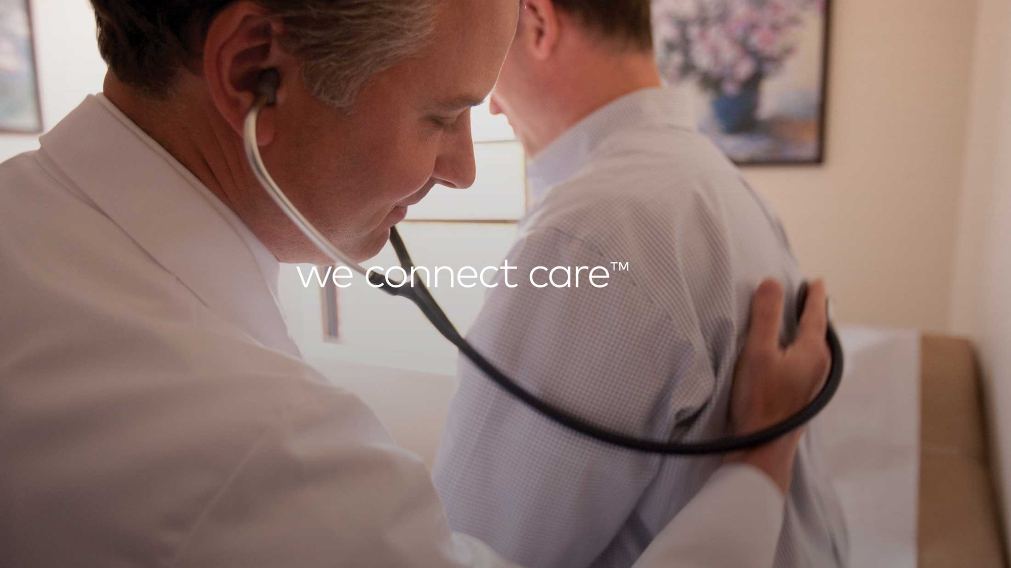 Athenahealth ad with words We Connect Care - doctor and a patient in an office during wellness checkup