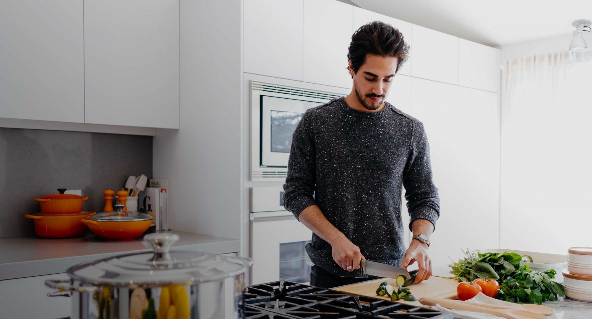 American Home Shield hero image - man meticulously preparing dinner in modern, well-lit kitchen