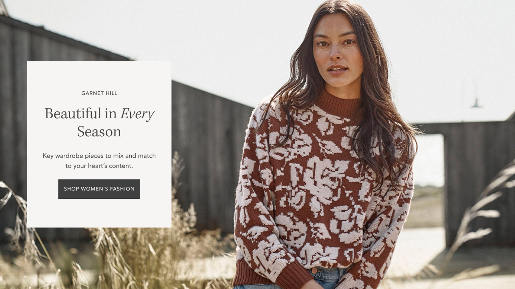 Garnet Hill website hero banner with woman modeling a sweater, text overlay in a white box
